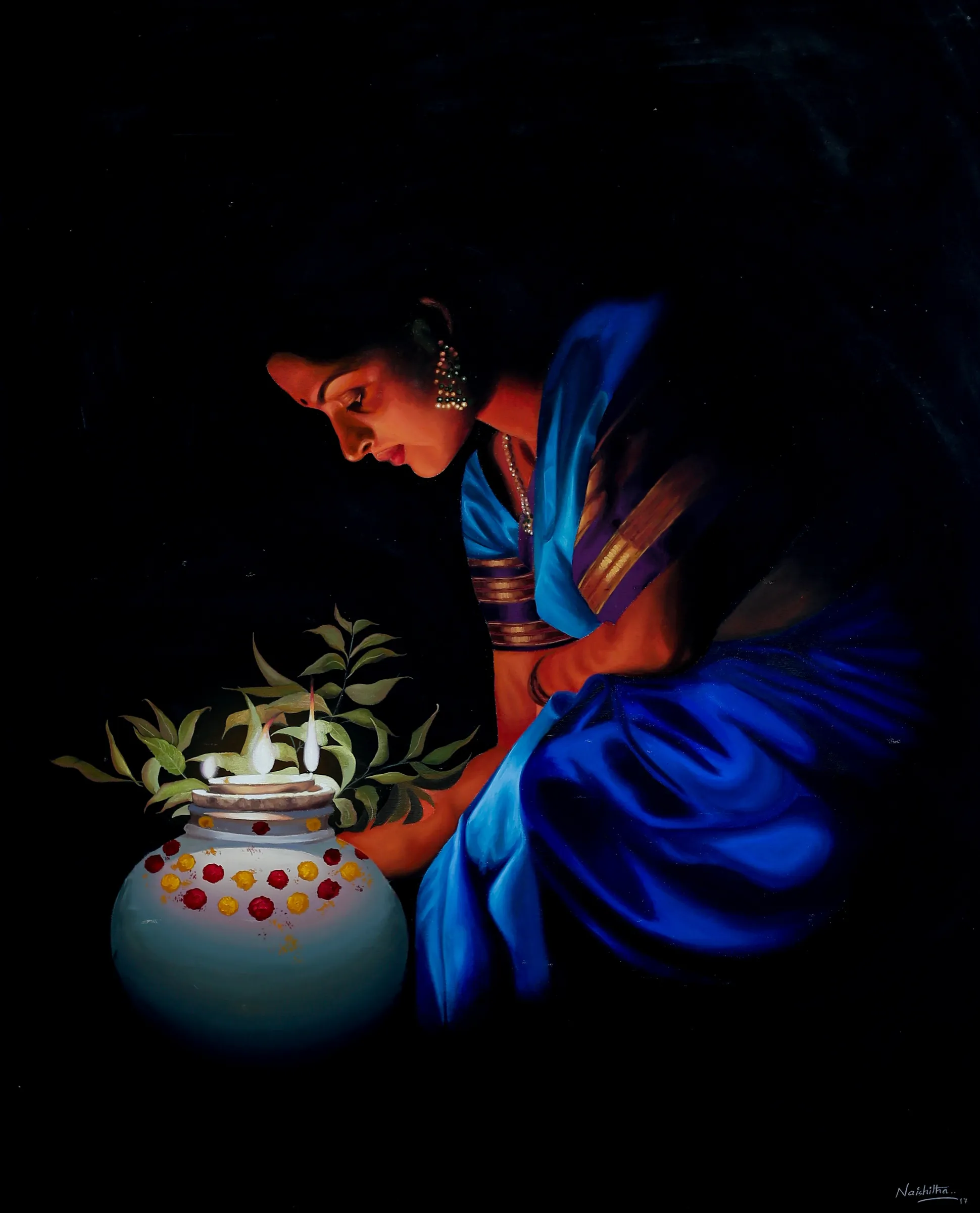 A woman in a blue sari lights a lamp in a painted pot, glowing in the dark